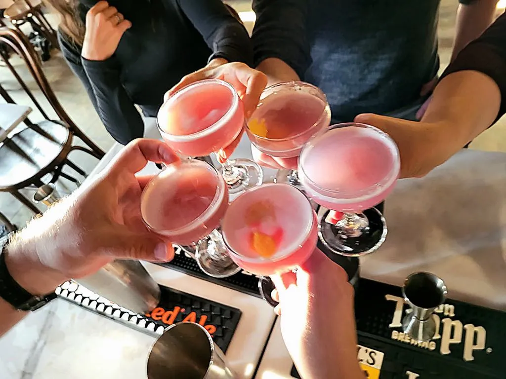 several people clinking their cocktail glasses together cheering