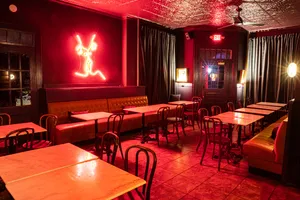 Unicorn's dining area, with moody red lighting and a neon sign of two people kissing